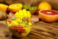 Tasty fruit salad in glass bowl and fresh fruits on wooden table Royalty Free Stock Photo