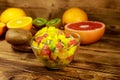 Tasty fruit salad in glass bowl and fresh fruits on wooden table Royalty Free Stock Photo