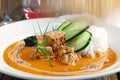 Tasty goulash with rice and vegetables on a wooden table.