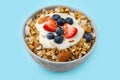 Tasty granola, yogurt and fresh berries in bowl on light blue background. Healthy breakfast Royalty Free Stock Photo