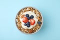 Tasty granola, yogurt and fresh berries in bowl on light blue background, top view. Healthy breakfast Royalty Free Stock Photo