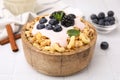 Tasty granola, yogurt and fresh berries in bowl on white tiled table, closeup. Healthy breakfast Royalty Free Stock Photo