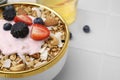 Tasty granola, yogurt and fresh berries in bowl on white tiled table, closeup with space for text. Healthy breakfast Royalty Free Stock Photo