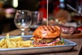 Tasty grilled burger with beef,cheese,bacon and sauce on wooden table with french fries and beer Royalty Free Stock Photo