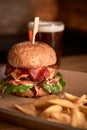 Tasty grilled burger with beef,cheese,bacon and sauce on wooden table with french fries and beer Royalty Free Stock Photo