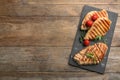 Tasty grilled chicken fillets with tomatoes and arugula on wooden table, top view. Space for text Royalty Free Stock Photo