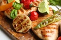 Tasty grilled chicken fillets with vegetables and lime on wooden board, closeup Royalty Free Stock Photo