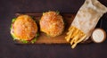 Tasty grilled home made burger with beef, tomato, cheese, cucumber and lettuce on a dark stone background. Top view. fast food and Royalty Free Stock Photo