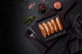 Tasty grilled sausages with spices and herbs on a black slate plate Royalty Free Stock Photo