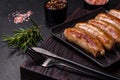 Tasty grilled sausages with spices and herbs on a black slate plate Royalty Free Stock Photo