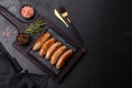 Tasty grilled sausages with spices and herbs on a black slate plate Royalty Free Stock Photo