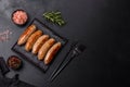 Tasty grilled sausages with spices and herbs on a black slate plate Royalty Free Stock Photo