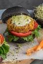 Tasty grilled veggie burger with chickpeas and vegetables on black bread on wooden background Royalty Free Stock Photo