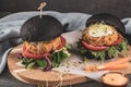 Tasty grilled veggie burger with chickpeas and vegetables on black bread on wooden background Royalty Free Stock Photo