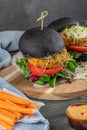 Tasty grilled veggie burger with chickpeas and vegetables on black bread on wooden background Royalty Free Stock Photo