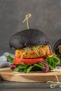 Tasty grilled veggie burger with chickpeas and vegetables on black bread on wooden background Royalty Free Stock Photo