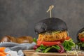 Tasty grilled veggie burger with chickpeas and vegetables on black bread on wooden background Royalty Free Stock Photo