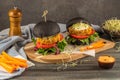 Tasty grilled veggie burger with chickpeas and vegetables on black bread on wooden background Royalty Free Stock Photo