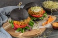 Tasty grilled veggie burger with chickpeas and vegetables on black bread on wooden background Royalty Free Stock Photo