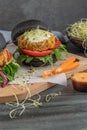 Tasty grilled veggie burger with chickpeas and vegetables on black bread on wooden background Royalty Free Stock Photo