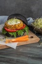 Tasty grilled veggie burger with chickpeas and vegetables on black bread on wooden background Royalty Free Stock Photo