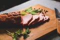 Tasty ham lying on the wooden panel plank. Meat with green leaves spinach. Food photo with pepper spices