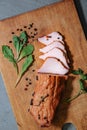 Tasty ham lying on the wooden panel plank. Meat with green leaves spinach. Food photo with pepper spices