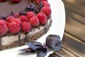 Tasty and harmless dessert background. Vegan chocolate cake with raspberries on white plate with basil leaves. Wooden Royalty Free Stock Photo