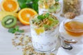 Tasty and healthy breakfast or snack: yogurt, granola and kiwi, orange, banana slices, honey, mint leaves on a white wooden backgr Royalty Free Stock Photo