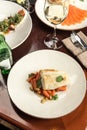 Tasty healthy fish fillet with baby carrots and glass of white wine wooden on table at restaurant Royalty Free Stock Photo