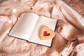 Tasty heart shape cookie with strawberry jam on open paper book over glowing lights close up. Royalty Free Stock Photo