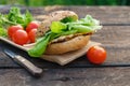 Tasty homemade burger and lettuce, tomatoes on wooden picnic table Royalty Free Stock Photo
