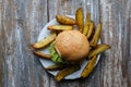 Tasty homemade cheeseburger with mustard, tomatoes and green lettuce. Sesame burgers with roasted potato wedges on wooden
