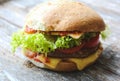 Tasty homemade cheeseburger with mustard, tomatoes and green lettuce. Sesame burgers on wooden background. Food photo