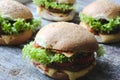 Tasty homemade cheeseburger with mustard, tomatoes and green lettuce. Sesame burgers on wooden background.