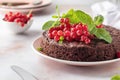 Tasty homemade chocolate cake brownie decorated with red currant berries and mint on white marble table close up Royalty Free Stock Photo