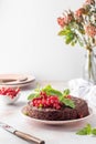 Tasty homemade chocolate cake brownie decorated with red currant berries and mint on white marble table with flowers and Royalty Free Stock Photo