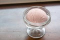 The tasty homemade cool strawberry ice cream scoop in glass cup on wood table