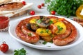 Tasty homemade grilled sausages with baked herb potatoes, mushrooms, cherry tomatoes and ketchup on a wooden background.