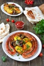 Tasty homemade grilled sausages with baked herb potatoes, mushrooms, cherry tomatoes and ketchup on a wooden background.