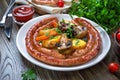 Tasty homemade grilled sausages with baked herb potatoes, mushrooms, cherry tomatoes and ketchup on a wooden background.