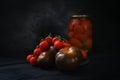 Tasty Homemade Tomatoes Preserves In Glass Jar. Fresh And Canned Tomatoes On Black Background