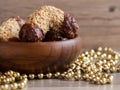 Homemade walnut rolls with dark chocolate in a wooden bowl and golden beads chain decoration, traditional Christmas sweets Royalty Free Stock Photo