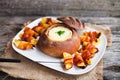 Tasty hot cheese fondue served in a bread roll with potatoes and Royalty Free Stock Photo