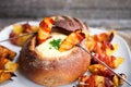 Tasty hot cheese fondue served in a bread roll with potatoes and Royalty Free Stock Photo