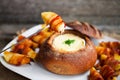 Tasty hot cheese fondue served in a bread roll with potatoes and Royalty Free Stock Photo