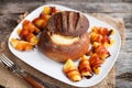 Tasty hot cheese fondue served in a bread roll with potatoes and Royalty Free Stock Photo