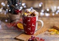 Tasty hot chocolate with marshmallows in a red Christmas cup against the blurry background of lights Royalty Free Stock Photo