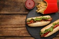 Tasty hot dogs, French fries and sauce on wooden table, flat lay with space for text. Fast food Royalty Free Stock Photo