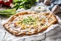 Tasty hungarian langos served with sour creme, ham, cheese, herbs and vegetables in the background